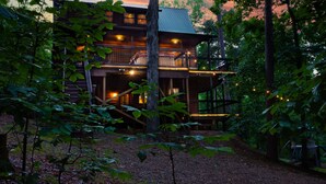 A two-story log cabin with a balcony, surrounded by trees and a wooden deck. - Fantastic 5-bedroom/Hot Tub/Pool Table/Games/Fire Pit/Foosball/Shuffleboard (Broken Bow)