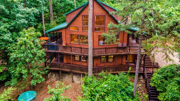 A log cabin with multiple levels, surrounded by dense forest. - Fantastic 5-bedroom/Hot Tub/Pool Table/Games/Fire Pit/Foosball/Shuffleboard (Broken Bow)