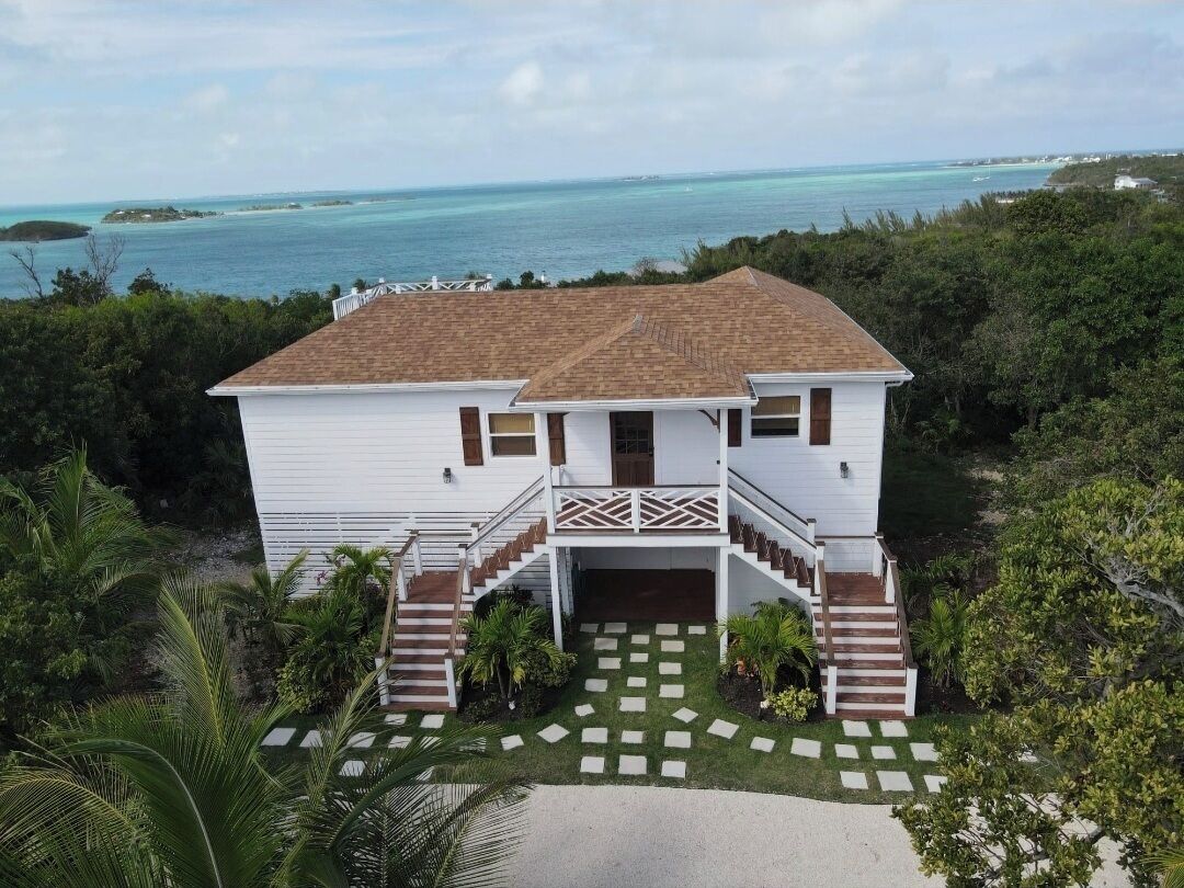 A two-story house with a balcony, a staircase, and a view of the ocean.