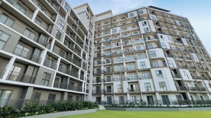 Un edificio residencial de varios pisos con balcones, techo plano y césped bien cuidado.