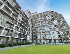 Ein mehrgeschossiges Wohnhaus mit Balkonen, einer flachen Dachterrasse und einem gepflegten Rasen.