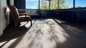 Ein überdachter Außenbereich mit Holzmöbeln und Blick zum Himmel.