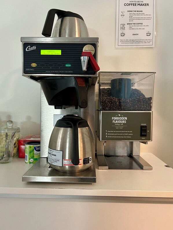 A coffee maker with a filter basket, a kettle, and a container of coffee beans. - Nordic Inn (Erickson)