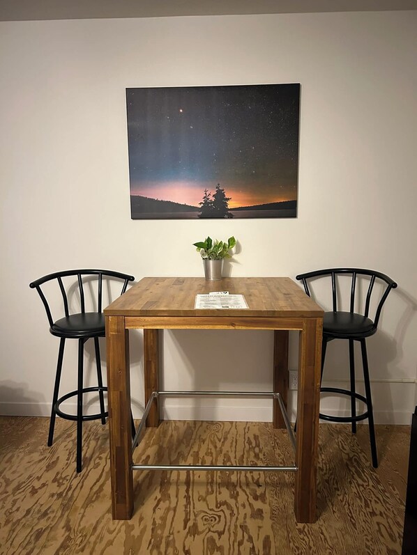 Un tavolo da pranzo con due sedie, una pianta in vaso e un quadro appeso al muro.