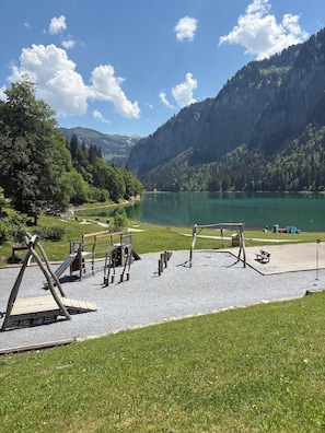 Ein Spielplatz mit Schaukeln, Rutschen, einer Bank und einem Kiesweg.