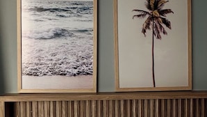 A bedroom with a bed, two framed pictures on the wall, and a wooden headboard. - W Tambaú (João Pessoa)