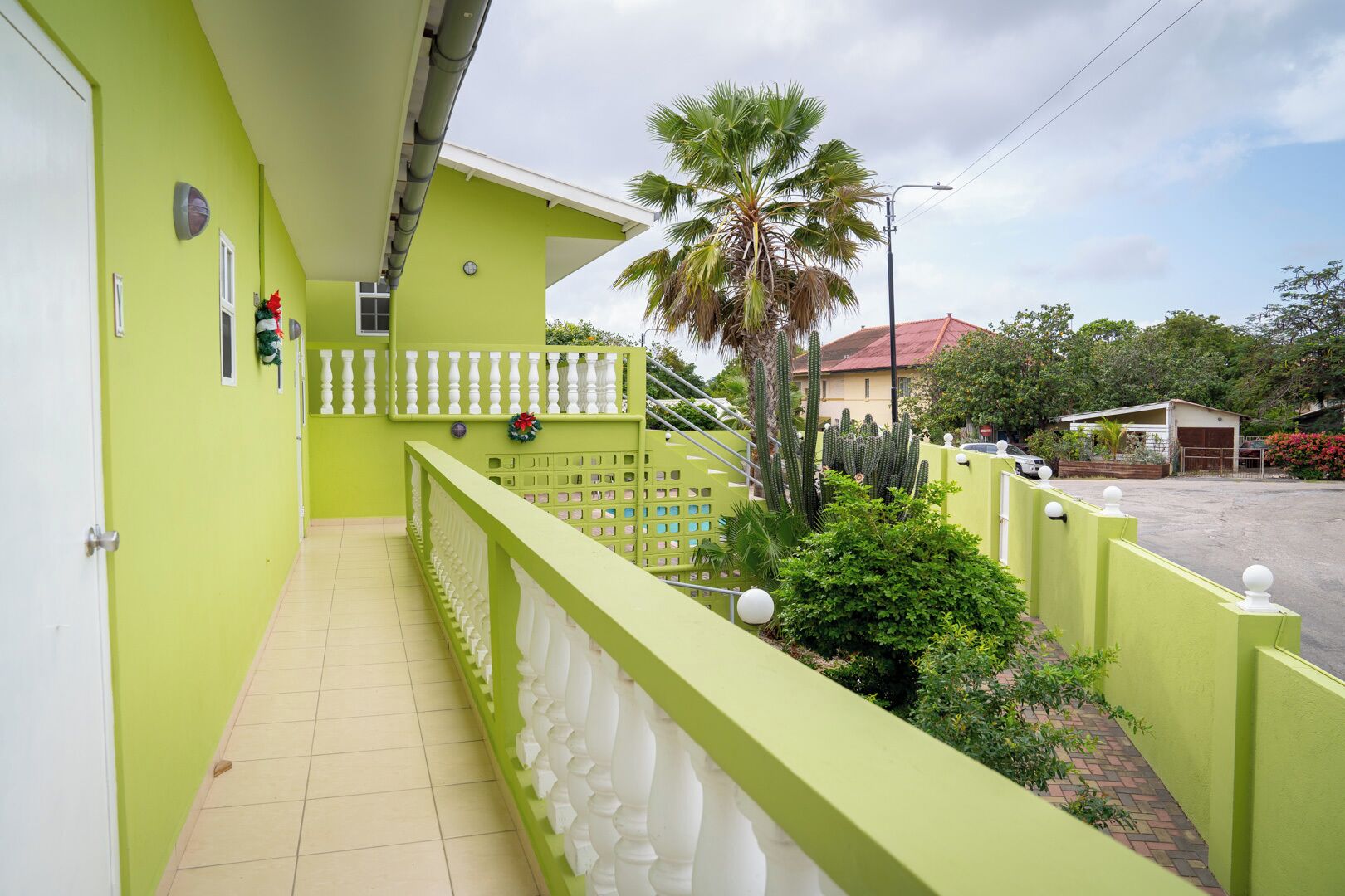A green exterior with a balcony, a palm tree, and a cactus garden.