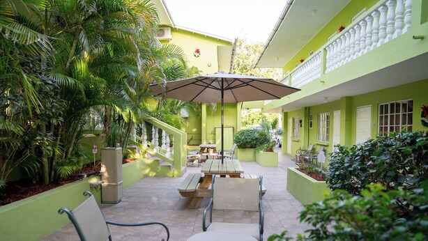 A courtyard with a dining area, outdoor seating, and lush greenery. - Apartamentu Holanda (Willemstad)