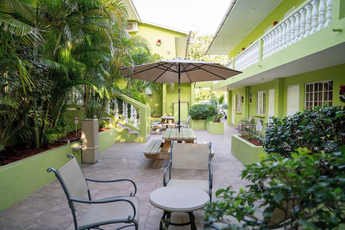Un patio con zona de comedor, asientos al aire libre y abundante vegetación.