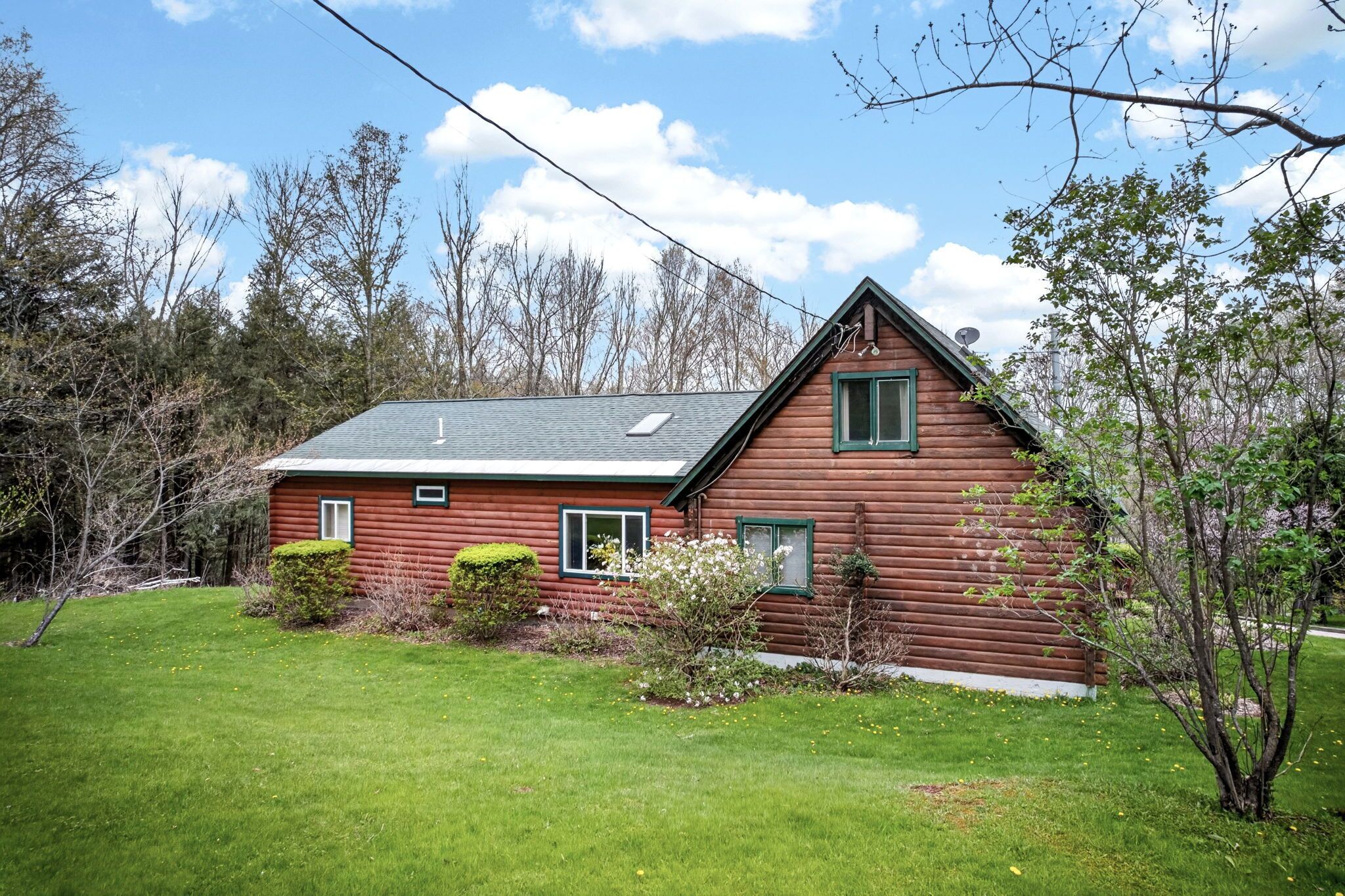 A wooden cabin with a sloped roof, a small porch, and a well-maintained lawn.