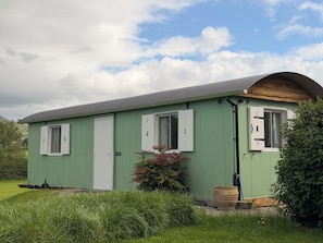 A single-story, green building with a sloped roof, white-framed windows, and a door labeled 'Office.'