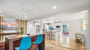 A modern kitchen with white cabinets, a central island, and blue bar stools.