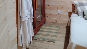 A wooden-paneled room with a bed, a wardrobe, and a door with glass panels. - Briar Ridge Cabin in Osgood IN (Osgood)