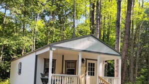 A small cabin with a porch, a staircase, and a view of the surrounding forest. - Briar Ridge Cabin in Osgood IN (Osgood)