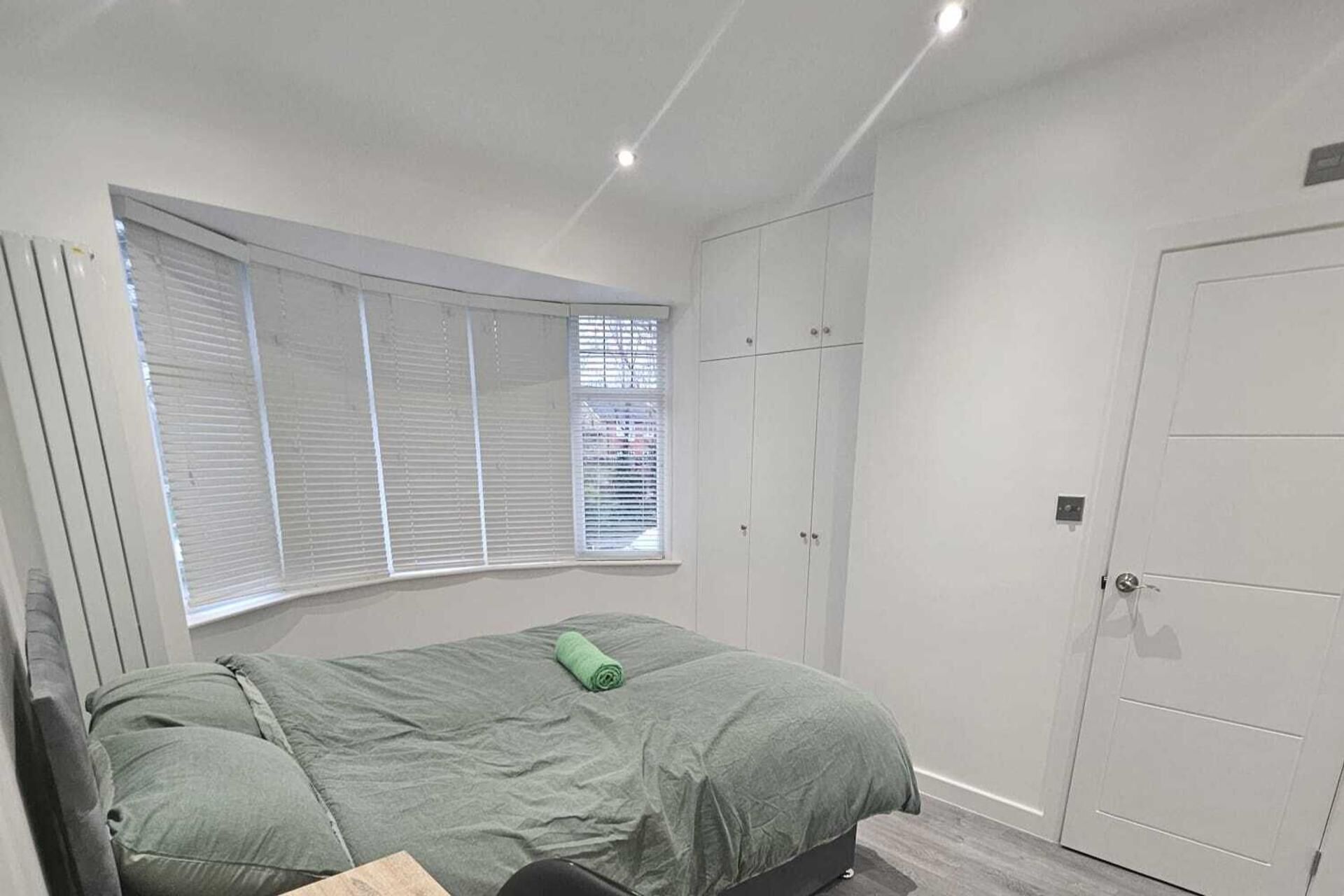 Un dormitorio con cama, armario y ventana con persianas.