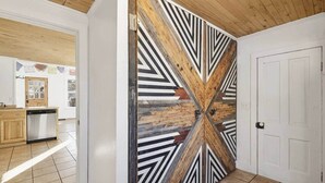 Un couloir doté d’un plafond en bois et orné d’une grande œuvre d’art murale aux motifs géométriques.