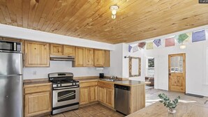 Une cuisine avec des meubles en bois, des appareils électroménagers en acier inoxydable et un sol carrelé.