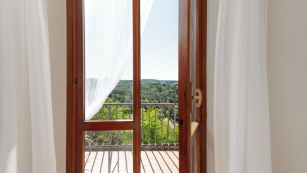 En balkon med gelænder af træ og udsigt over et grønt landskab.