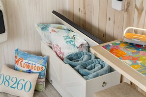 Eine weiße Schublade mit einem blauen Kissen, ein Kissen mit der Aufschrift 'Wildwoods' und ein Kissen mit der Aufschrift '08260'.
