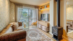 Una sala de estar acogedora con sofá, alfombra estampada, chimenea y vistas a través de un ventanal.