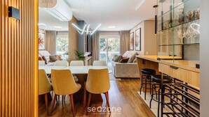 Una sala moderna con comedor, una cocina con vitrina de vidrio y una zona de bar.