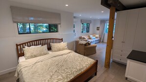 A bedroom with a wooden bed, a sofa, and a wardrobe. - Urban Forest 2 Bedroom+ suite in Mid Century Architect's Home (Victoria)