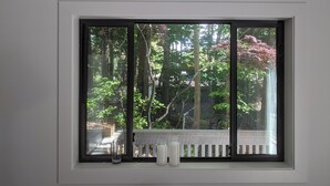 A window with a view of a wooden deck and trees. - Urban Forest 2 Bedroom+ suite in Mid Century Architect's Home (Victoria)