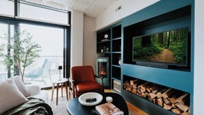 Uma sala de estar moderna com lareira, uma televisão grande na parede e um espaço de estar aconchegante.