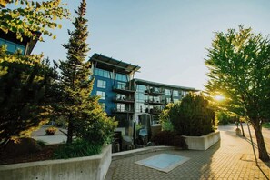 A modern building with a glass facade, surrounded by trees and a paved walkway. - Timeless Modern Luxury at Bellerive on the River (Coeur d'Alene)