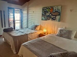 Ein Zimmer mit zwei Betten, einem Bild an der Wand und einem Fenster mit Jalousien.