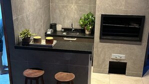 Een moderne keuken met een donker aanrecht, twee krukken, een spoelbak en een inbouwoven.