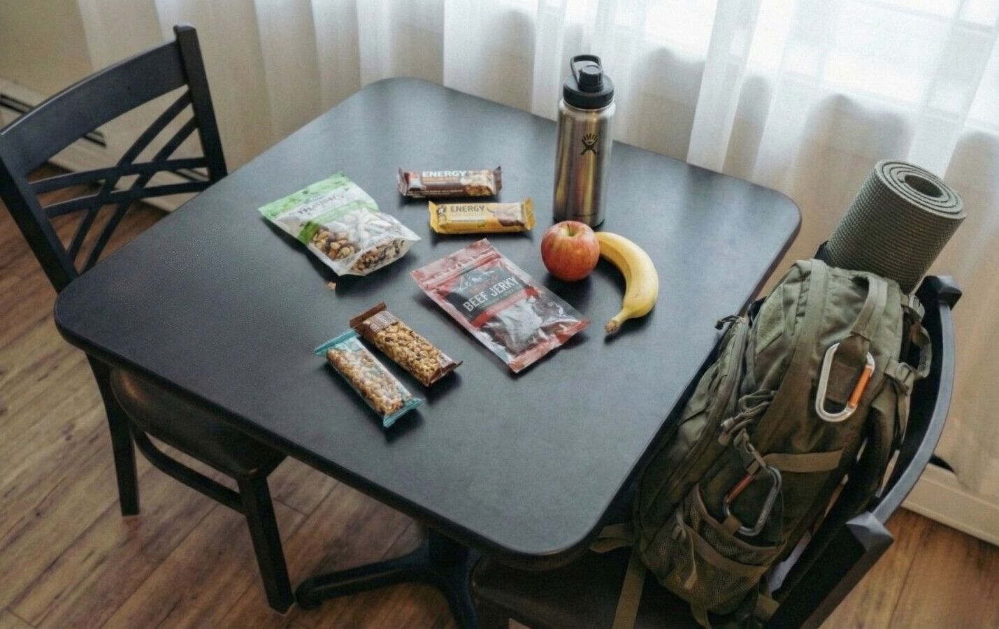 A table with snacks, a thermos, a banana, and a rolled-up mat.