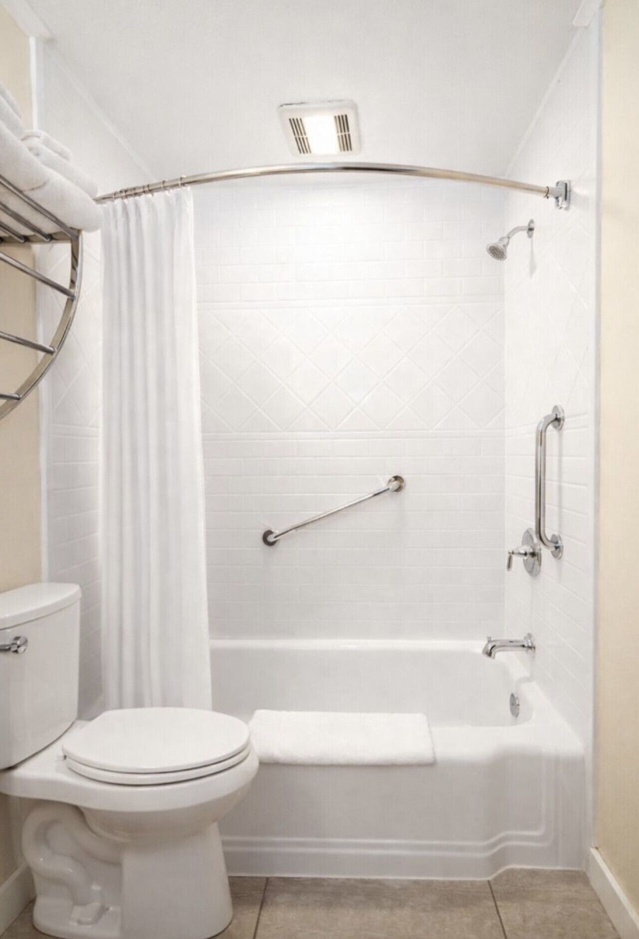 A bathroom with a white toilet, a bathtub, and a shower with grab bars.