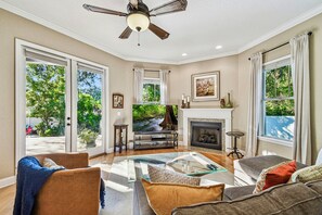 Un salon avec une cheminée, un téléviseur et un ventilateur de plafond.