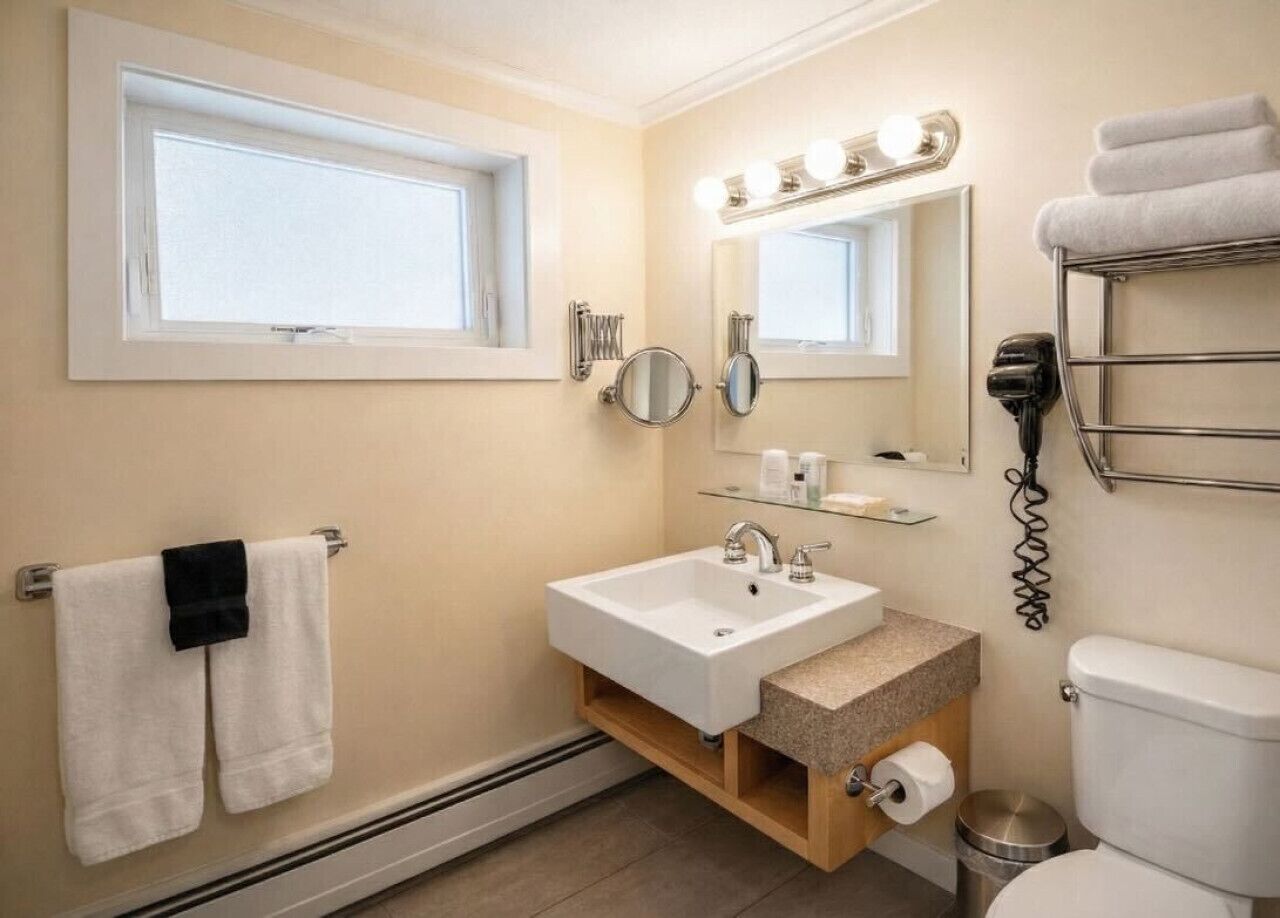A bathroom with a sink, mirror, vanity, towel rack, and a toilet.