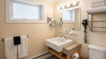 A bathroom with a sink, mirror, vanity, towel rack, and a toilet.