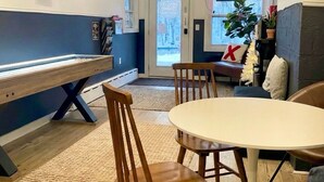 Un coin repas comprenant une table ronde, deux chaises en bois, un banc et un lustre.