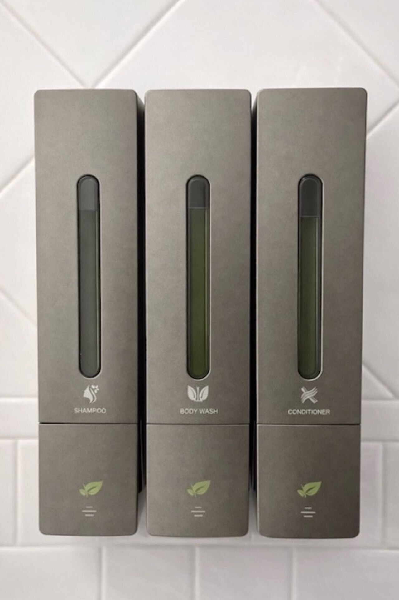 Three gray boxes labeled 'SHAMPOO,' 'BODY WASH,' and 'CONDITIONER' on a white tiled wall.