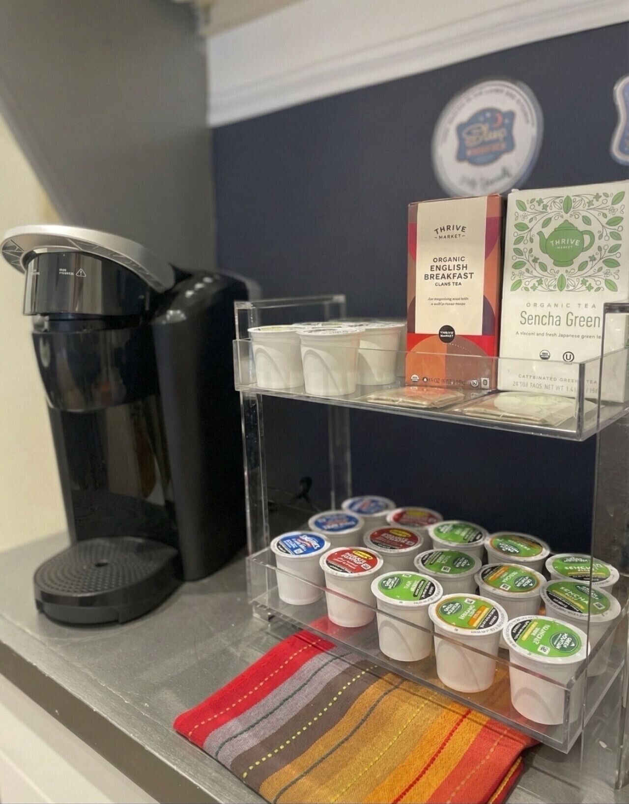 A coffee machine, a display of tea boxes, and a shelf with tea containers.
