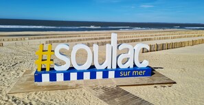 Een strandbordes met het woord 'soulac' en 'sur mer' op een houten looppad.