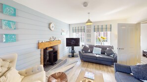A living room with a fireplace, a flat-screen TV, a sofa, and a coffee table. - Seaview Cottage -  a luxury 2 bed cottage that sleeps 4 guests  in 2 bedrooms (Filey)