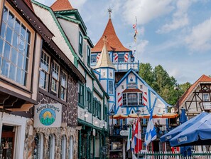 A traditional European street with historic buildings, a sign for Alpine Trading Co., and flags. - Seconds from Helen Main St! Hot Tub - 4 bedrms - Sleeps 9 (Helen)