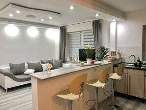 A modern kitchen with a central island, bar stools, a sofa, and a dining area. - Aparts House Essen (Essen)