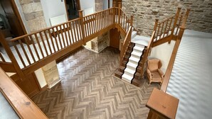 Eine Holztreppe mit Fischgrätparkett, Steinwänden und Blick auf einen Raum mit weißer Decke.