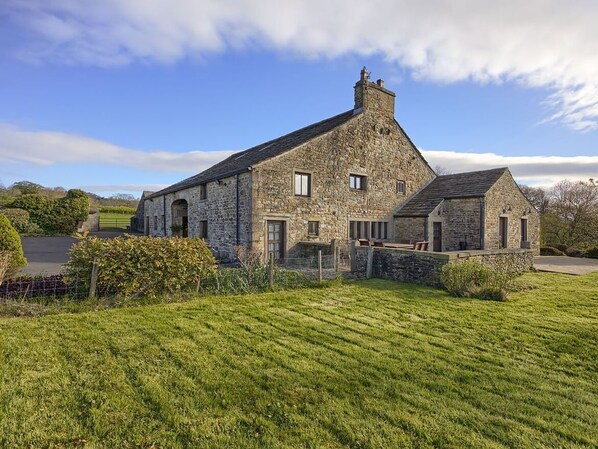 A stone building with a sloped roof, a small porch, and a fenced yard.