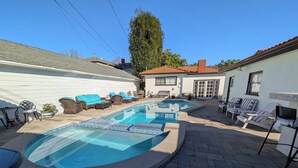 Un giardino con piscina, sedie a sdraio e un'area patio.