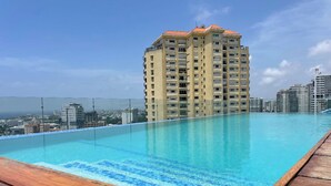 A rooftop infinity pool with a wooden deck, surrounded by high-rise buildings. - Exclusive 3 Suite Luxury Panoramic_Pool_Cinema_Gym (Santo Domingo)