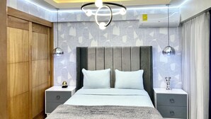 A modern bedroom with a large bed, two bedside tables, a wooden wardrobe, and a ceiling light fixture. - Exclusive 3 Suite Luxury Panoramic_Pool_Cinema_Gym (Santo Domingo)