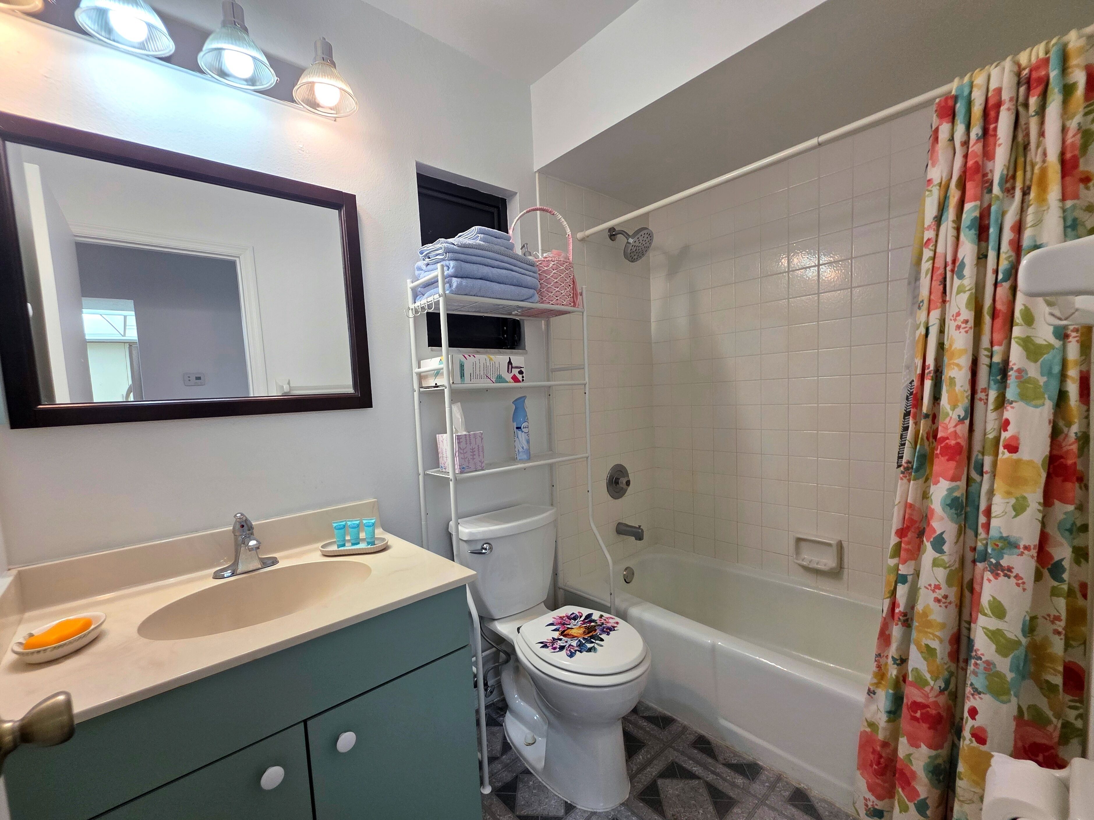 Baño con lavamanos, espejo, inodoro y ducha.