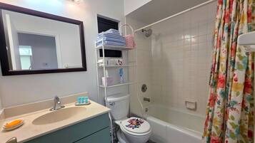 Baño con lavamanos, espejo, inodoro y ducha.